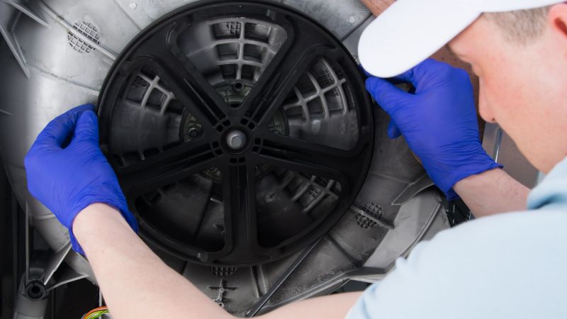 un technicien en train de changer la courroie d une machine a laver