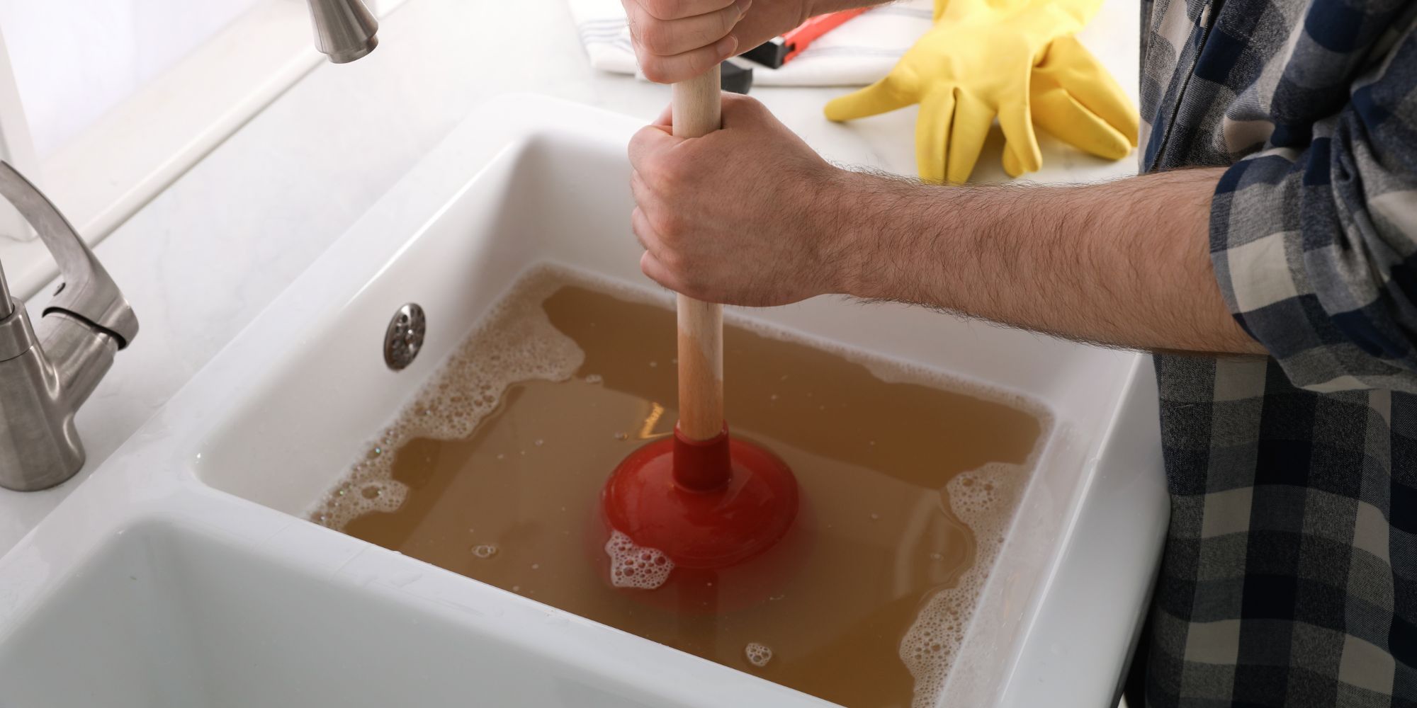 Plombier en train de tenter de déboucher une canalisation d'un évier