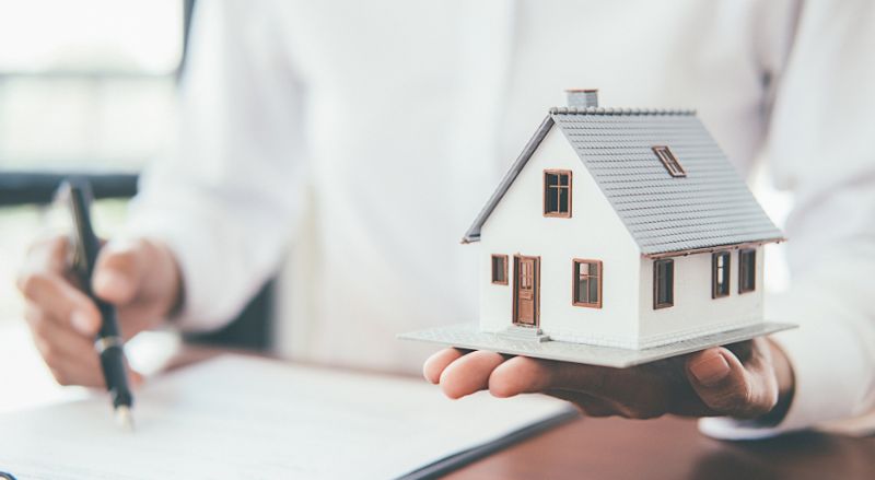 maquette de maison de 100 m2 avec un professionnel en train de noter des calculs on pourrait imaginer qu il evalue la consommation d une pompe a chaleur selon l etat de la maison