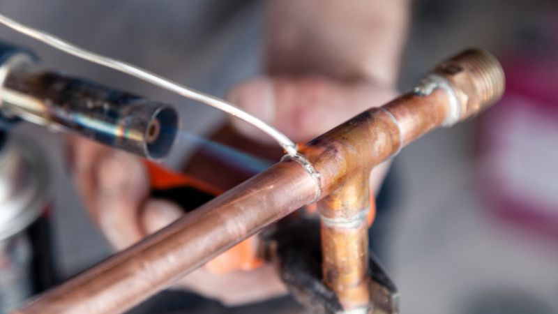 gros plan d un plombier ressoudant un tuyau en cuivre