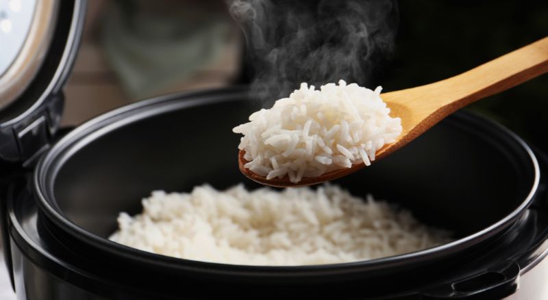 cuillere de riz fumant au dessus d un cookeo pour illustrer les recettes possibles avec la cuisson sous pression