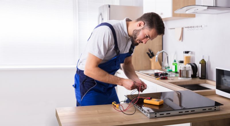 technicien reparant une plaque a induction dans une cuisine