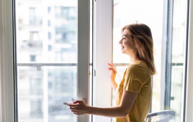 femme souriant en ouvrant sa fenêtre
