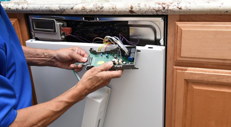 gros plan d un reparateur d appareils electromenagers debranchant le panneau de commande d un lave-vaisselle qui ne s allume plus
