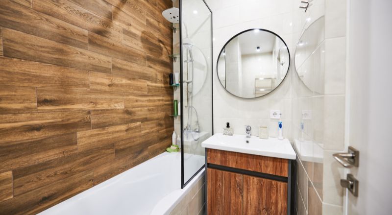 petite salle de bain avec baignoire dont la paroi de douche est adjacente au meuble vasque