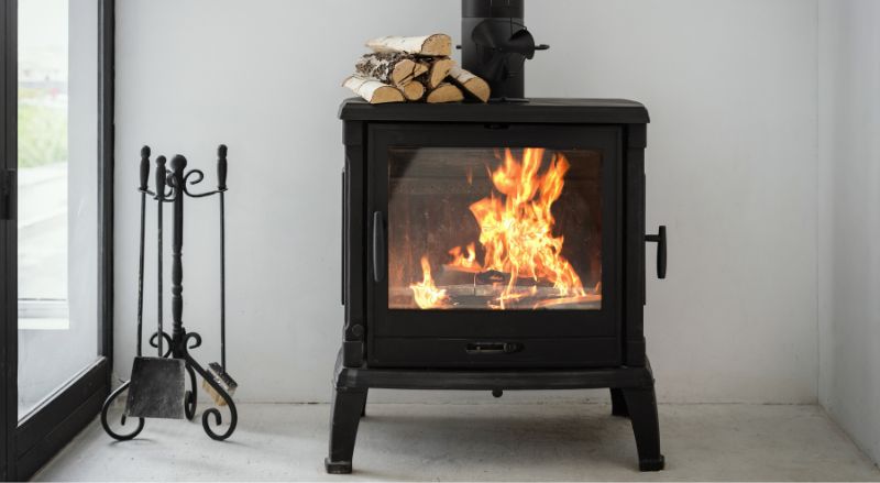 poele a bois en fonte noir avec un feu actif dans un interieur moderne et blanc