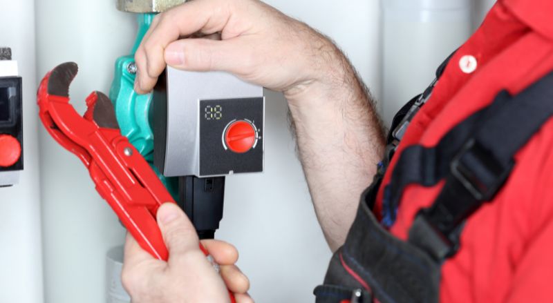 un artisan en train de changer ou de regler un circulateur de chauffage
