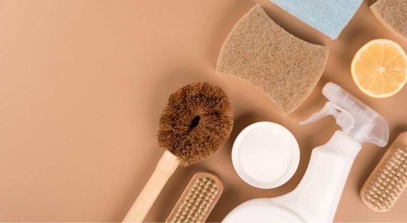 nettoyants menagers ecologiques et accessoires de menage poses a plat sur un fond orange