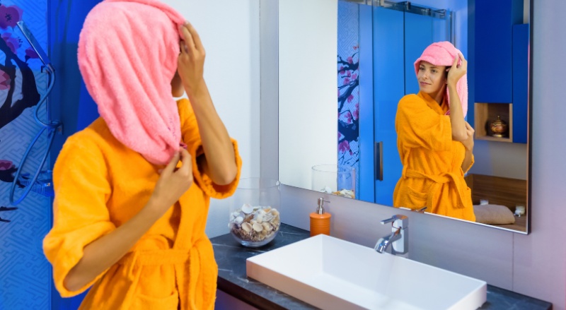 femme sortant de la douche avec un peignoir et une serviette