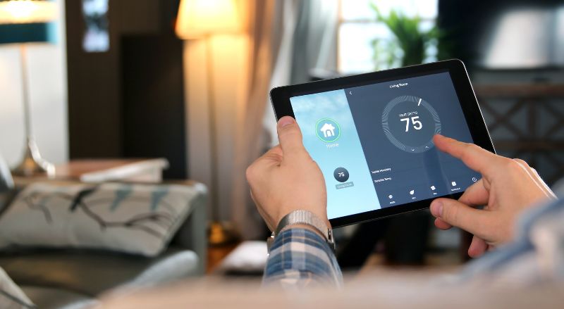 un homme ajuste une temperature avec une tablette avec une application de maison intelligente dans un salon moderne