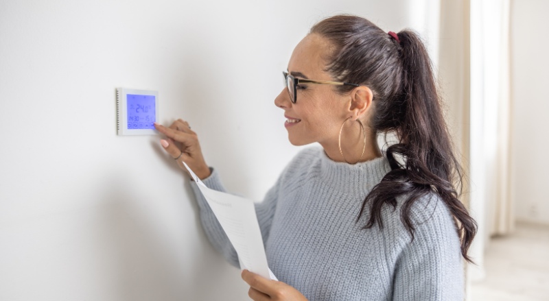 femme réglant le thermostat d'un radiateur