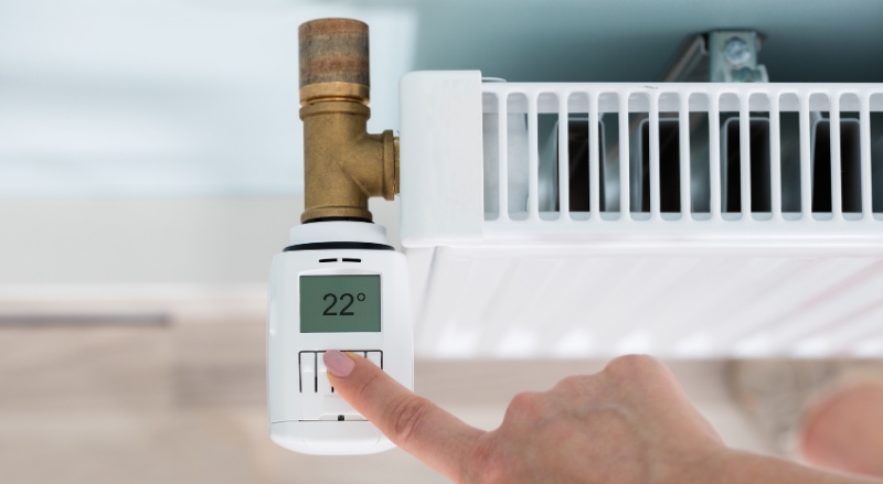 personne réglant le thermostat d'un radiateur